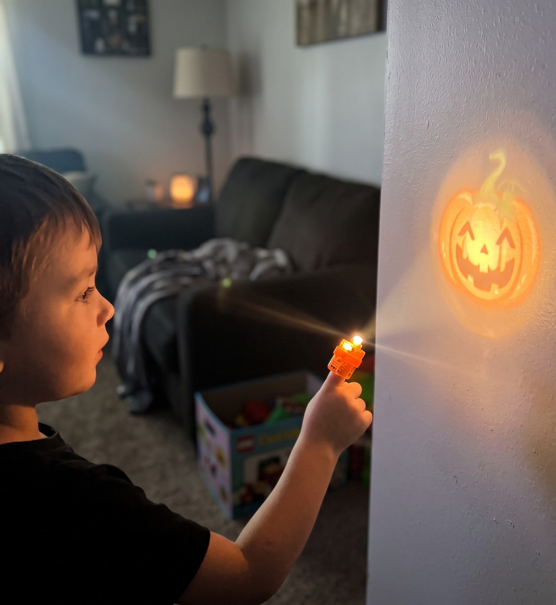 Child projecting a pumpkin image on a wall with a finger projector