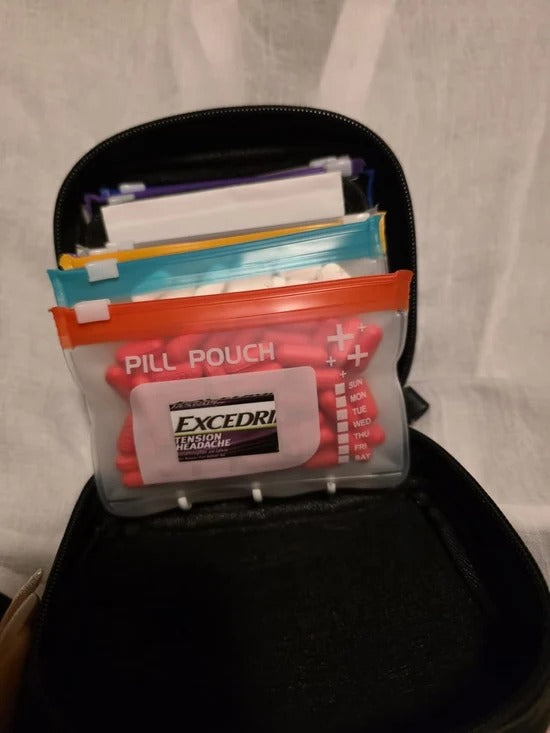 Black organizer case with labeled zipper pouch holding daily pills